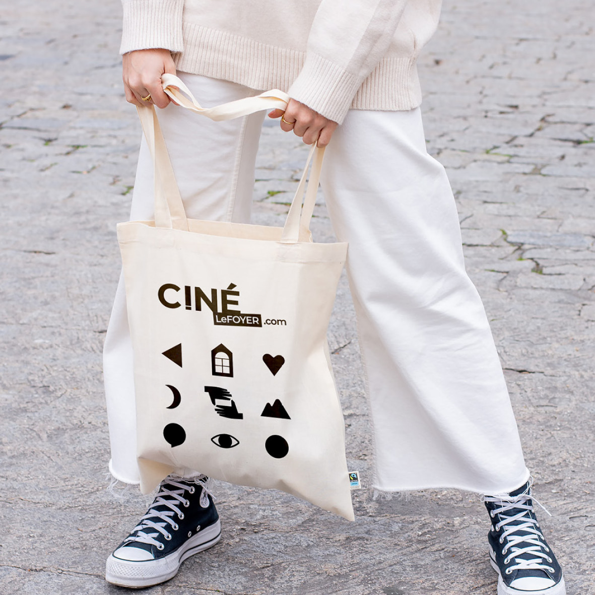 personne dans la rue tenant un tote bag avec logo et pictos du cinéma le foyer