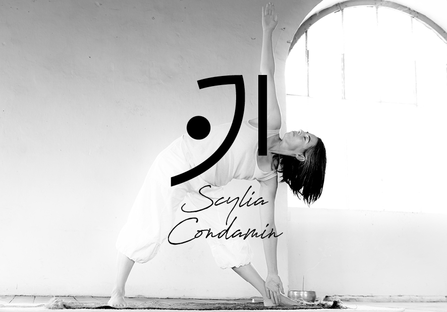 logo et signature scylia condamin en dessous en noir sur une photo noir et blanc de scylia condamin en plein cours de yoga devant un mur et une fenetre