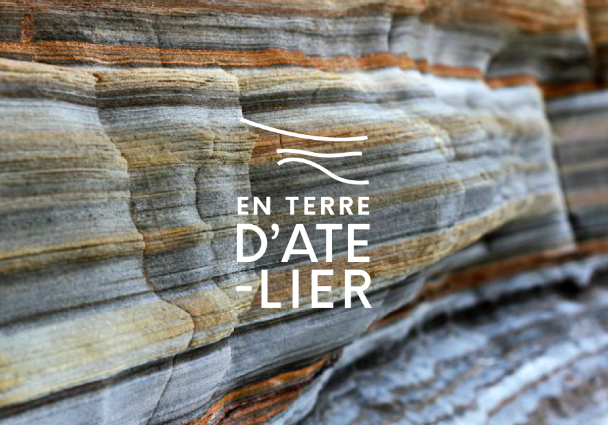 logo en terre d atelier blanc sur photo d une falaise avec aspect rayures de couleurs ocre gris et rouille